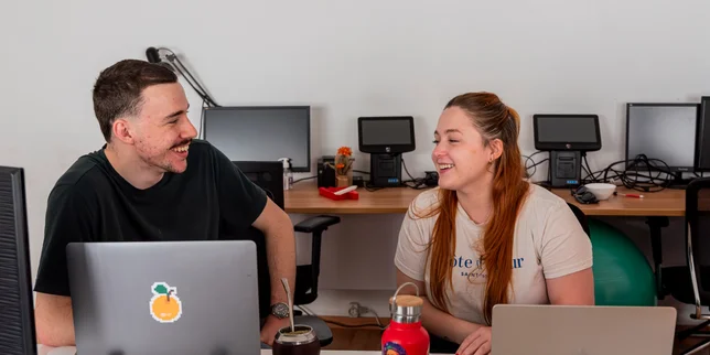 Two teammates sharing a laugh at their desks