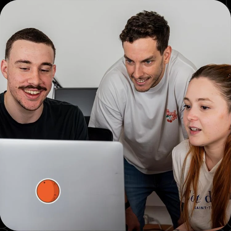 Three OrangeLoops teammates looking at a laptop together